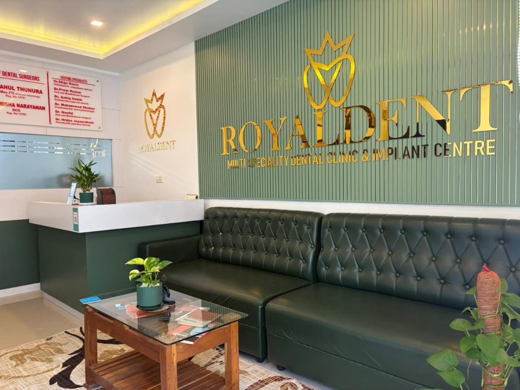 Royaldent Multi Speciality Dental Clinic Gold Logo & Green Lounge Seating in Vadakara